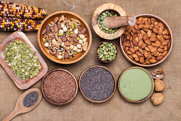 selection of healthy and clean food: seeds, superfoods, nuts, beans, biscuits on burlap background.