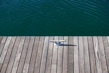 Wooden dock with mooring cleat, rippling blue-green waves in background, serenity, relaxation,...