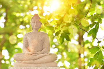 Buddha statue on green blurred nature background. Buddhist holy days concept.