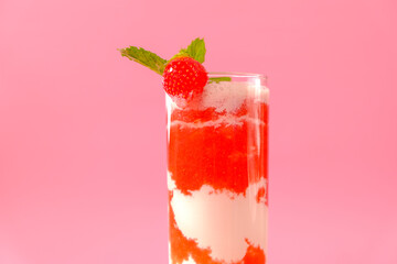 Strawberry cocktail with cream.Berry smoothies. Pink cocktail and cream in a transparent goblet with strawberries and sprigs of mint on a pink background.Delicious and healthy Drink 