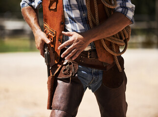 Ready to blow you away. Cropped shot of an unrecognizable cowboy drawing his gun.