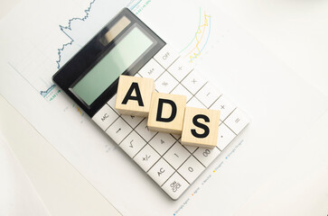 A businessman holds wooden cubes with a word ADS on a white background, with space to copy the text, business concept