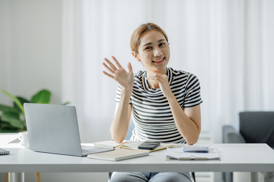Image of young pleased happy cheerful cute beautiful Asian business woman sit indoors using laptop computer smart female working at home,E learning working at home concept