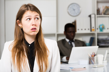 Fototapeta premium Portrait of upset woman and man colleague working with laptop on background in office
