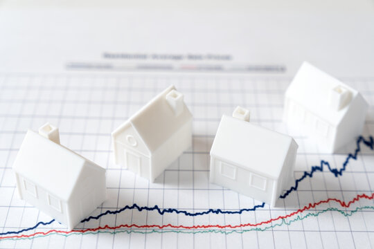 White miniature house models on graph indicating growth in real estate prices market