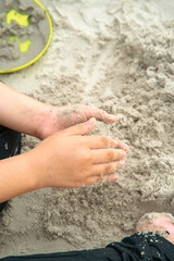 Child playing sand with hands at the beach.