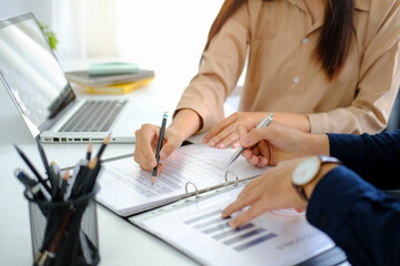 Cropped image of businesspeople analysing financial graph at office desk.