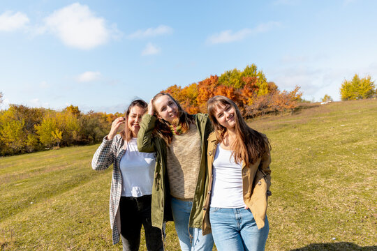 Three running girls at green grass at background of blue sky with clouds. Girlfriend concept.