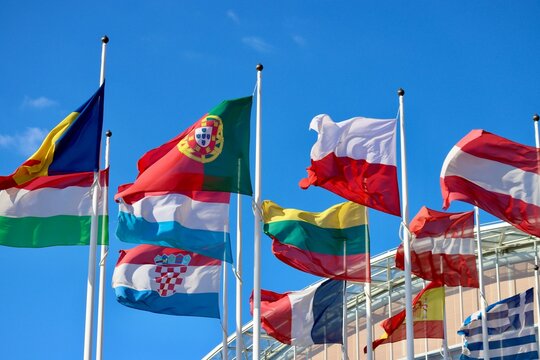 Group of EU memberstate flags waving in wind by EIB building in Luxembourg: Romania, Hungary, Portugal, Poland, Luxembourg, France, Lithuania, Latvia, Austria, Spain, Croatia, and Greece