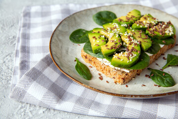 Toast with avocado, cottage cheese, spinach, sesame seeds, flax seeds. Healthy food rich in fiber, trace elements, omega acids, unsaturated lipids.