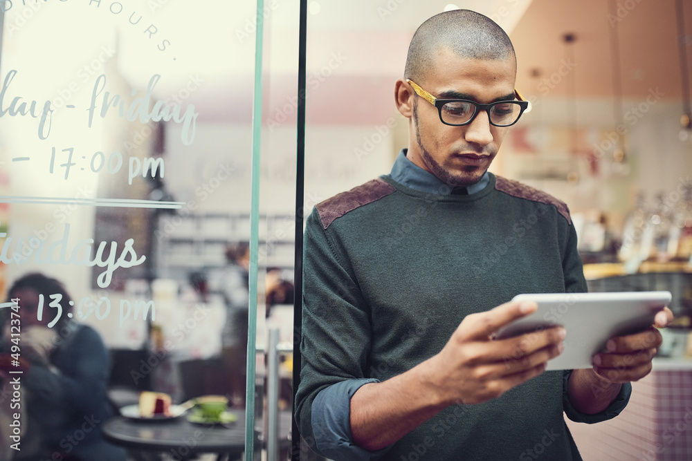 Poster keeping an eye on his competition. shot of a man using his digital tablet while standing in the entr