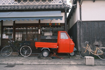 old 3 wheeled red truck in the street in Japan
