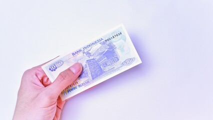 Indonesian Rupiah the official currency of Indonesia. Male hand showing Indonesian Rupiah note. Business Investment Economy Money and Finance Concept Uang 1000 Rupiah Kuno Vintage and ancient concept.