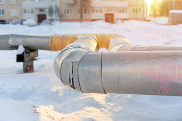 Central heating pipes sheathed with aluminum sheets in winter in Russia. Apartment building in the...