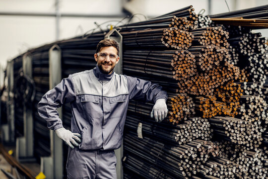 Portrait of proud metallurgy worker leaning on metal framework in steel factory.