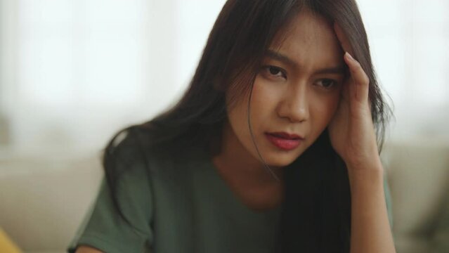 Upset asian woman frustrated by problem with work or relationships, sitting on couch, feeling despair and anxiety, loneliness, having psychological trouble