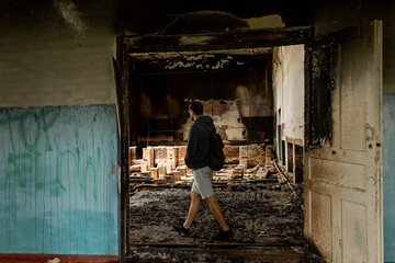 Destroyed building. Burnt building . Broken windows with ash . A man in a destroyed burnt building .