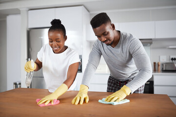 A little elbow grease makes a home shine. Shot of a young couple cleaning the kitchen counter at...