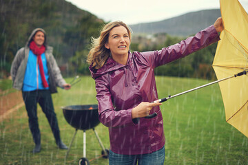 We wont let a little bad weather stop our barbeque. Shot of a couple trying to barbecue in the rain.