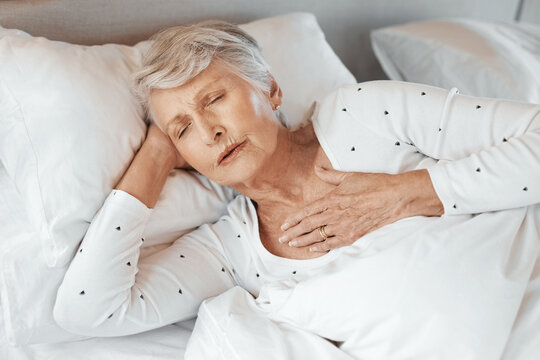 It can happen to anyone. Shot of a senior woman experiencing chest pain in bed in a nursing home.