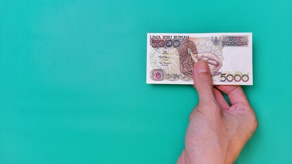 Indonesian Rupiah the official currency of Indonesia. Man's hand is making a payment. Male hand...
