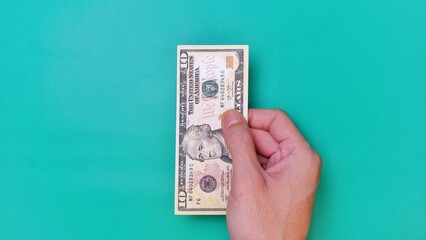 Man's hand is making a payment. Business Investment Economy Money Loan Saving Income and Finance concept. Male hand showing dollar bills on green background. Ten Dollar. 10 USD. Prosperity concept.
