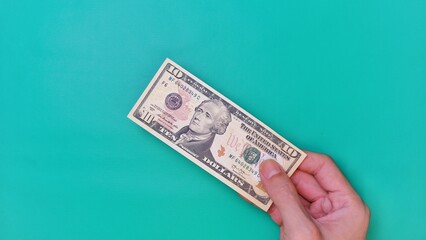 Man's hand is making a payment. Business Investment Economy Money Loan Saving Income and Finance concept. Male hand showing dollar bills on green background. Ten Dollar. 10 USD. Prosperity concept.