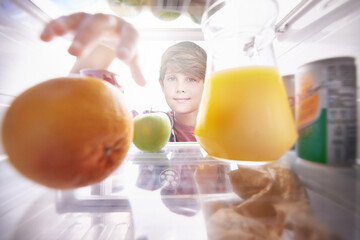 Making the right choice.... Shot of a young boy reaching into the fridge for a snack.