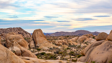 Fototapeta na wymiar Sparse and remote landscape in the Californian desert during sunset with clouds starting to build color. 