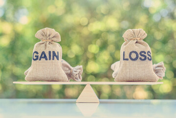 Capital investment gain and loss, financial concept : Gain and loss bags on a basic balance scale, depicts balancing between profit and loss while managing assets e.g bonds, stocks, derivatives, ETFs - obrazy, fototapety, plakaty