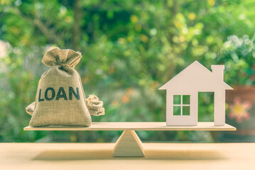 Home loan, reverse mortgage and saving for a real estate concept : House model, loan bag on basic balance scale, depicts saving for a house or flat manageable and turn a home buying dream into reality - obrazy, fototapety, plakaty