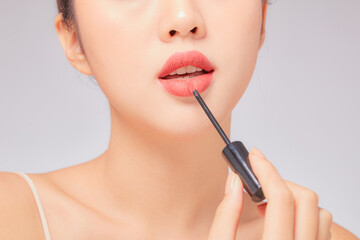 Front view of model using lipstick in white background for cosmetic advertising 