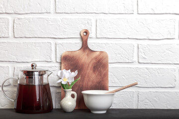 Kitchen background, white brick wall in loft style. Teapot and honey on the table. Morning tea