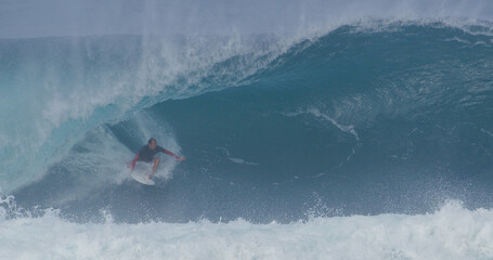 Surfer surfing big wave barrel tube