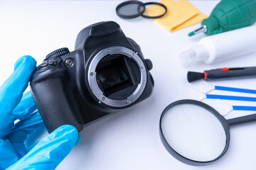 A gloved photographer holds his DSLR camera without a lens before cleaning the sensor