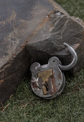 Old vintage iron padlock front of Huge stone on grass background. Selective focus.