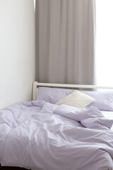 Bed with purple linen. Minimalistic modern stylish bedroom interior.