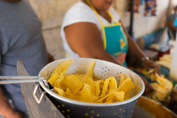 A Latin woman tends her retail business on the street and cooks fried sliced plantains with her husband outside a school in Managua, Nicaragua. Concept of fast food in Latin America.