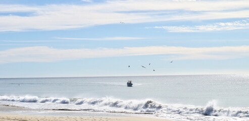Fototapeta na wymiar view of crashing waves on the beach with a boat