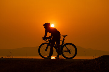 Fototapeta na wymiar silhouette of a cyclist on sunset, the scenery sunrise in the morning in Thailand.