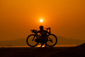 Obraz na płótnie Canvas silhouette of a cyclist on sunset, the scenery sunrise in the morning in Thailand.