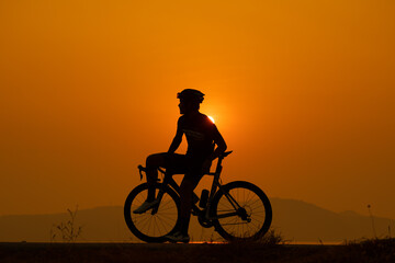 Fototapeta premium silhouette of a cyclist on sunset, the scenery sunrise in the morning in Thailand.
