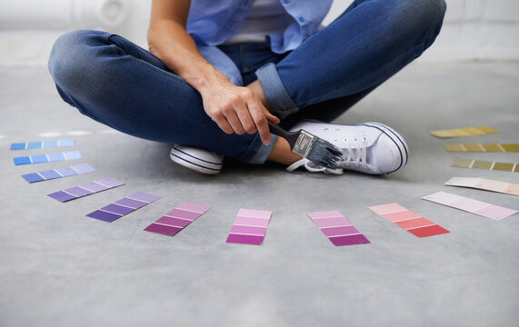 Purple for posperity. Shot of a female sitting crossed legged chosing paint colours.