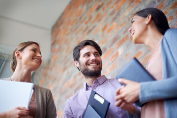 Catching up before the meeting. Shot of a coworkers talking to each other in a office hallway.