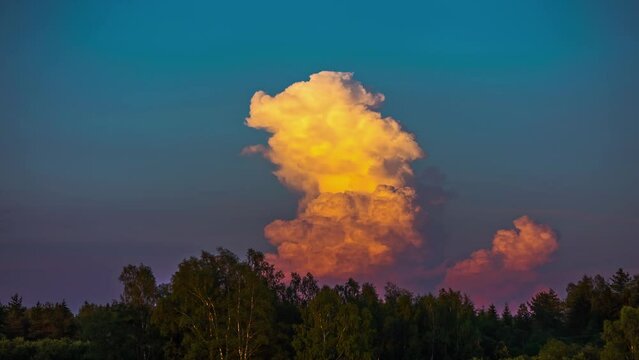 Sunlight falling onf moving storm tropical clouds at sunset in timelapse over green trees forest during sring season.