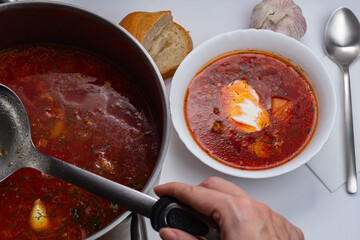 National food on white background. Freshly prepared Russian borscht in saucepan and in white bowl.