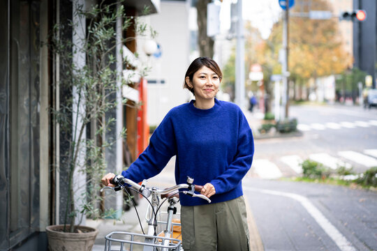 自転車を押して街を歩くミドル世代の日本人女性