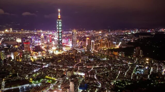 Aerial hyperlapse of Downtown Taipei at dusk, vibrant capital city of Taiwan, with 101 Tower standing out amid skyscrapers in XinYi Commercial District and city lights dazzling under blue twilight sky