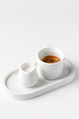 One coffee cup with espresso in morning on white tray with milk on white table. Aroma, ristretto. Mug of coffee. Close up. Breakfast