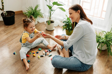 Mom and little daughter at home sculpt from plasticine and play together. The concept of preschool or home education